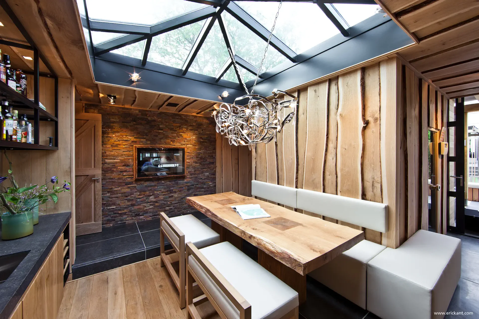 High-end eetruimte in project City Garden met glazen dakconstructie, boomstamtafel, natuurstenen wand en houten wandbekleding door ERIC KANT.