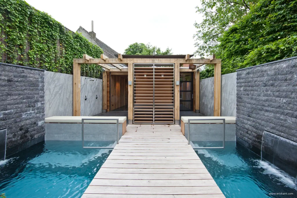 High-end zwembad in project City Garden met houten vlonderpad, eikenhouten pergola, natuurstenen wanden en watervallen door ERIC KANT.