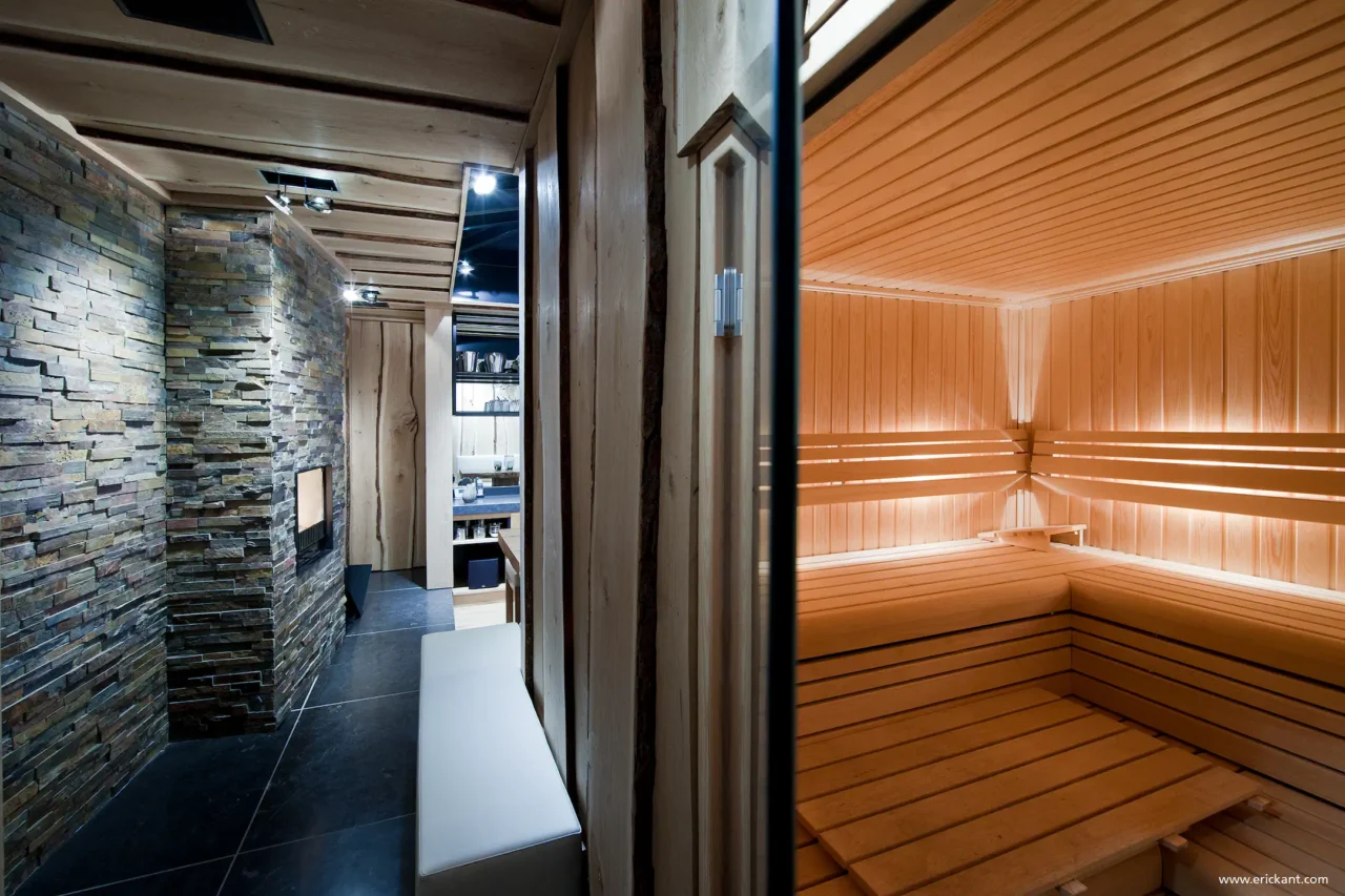 High-end houten sauna grenzend aan een gang met natuurstenen wand en haard in project City Garden door ERIC KANT.