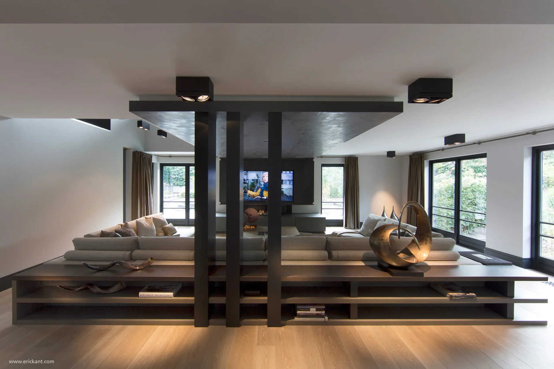 High-end woonkamer in project Family Country House met een symmetrisch houten maatwerk meubel achter de bank, zwarte verticale kolommen en een eikenhouten vloer door ERIC KANT.