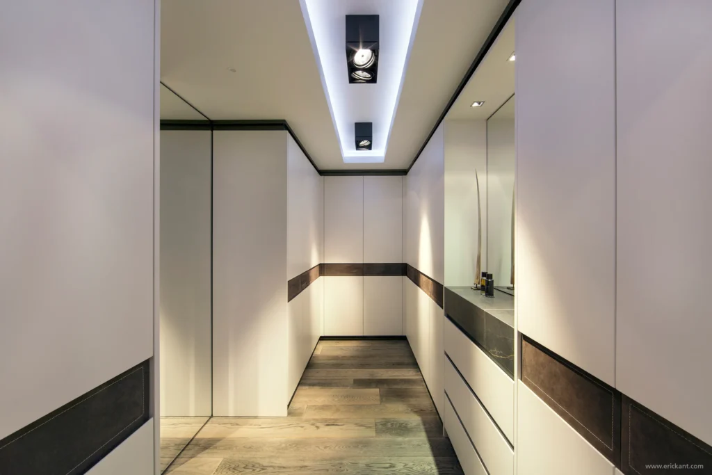 High-end inloopkast in project Family Country House met witte kastenwanden, lederen accenten, indirecte plafondverlichting en een eikenhouten vloer door ERIC KANT.