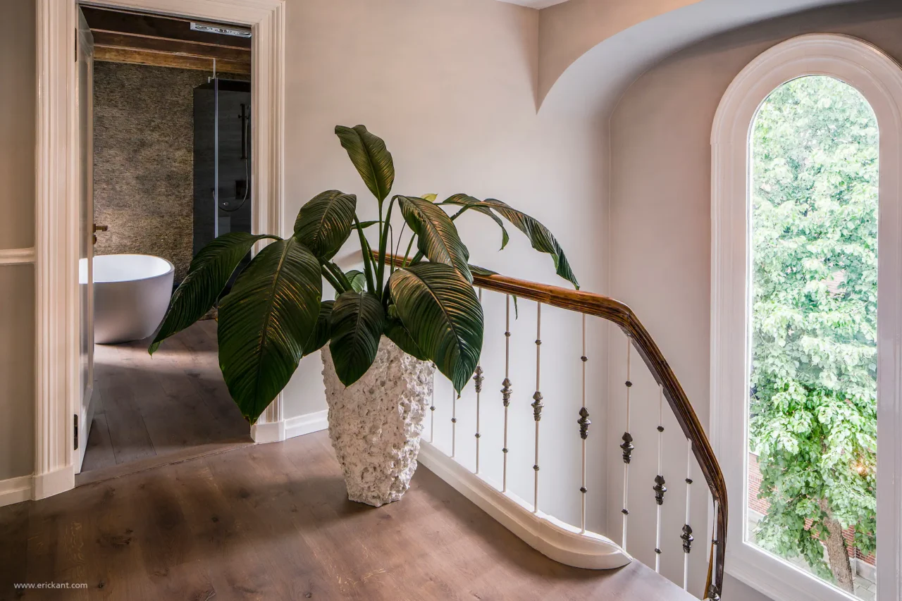 High-end overloop in Riga met klassieke trap, authentiek rond raam en doorkijk naar de luxe badkamer door ERIC KANT.