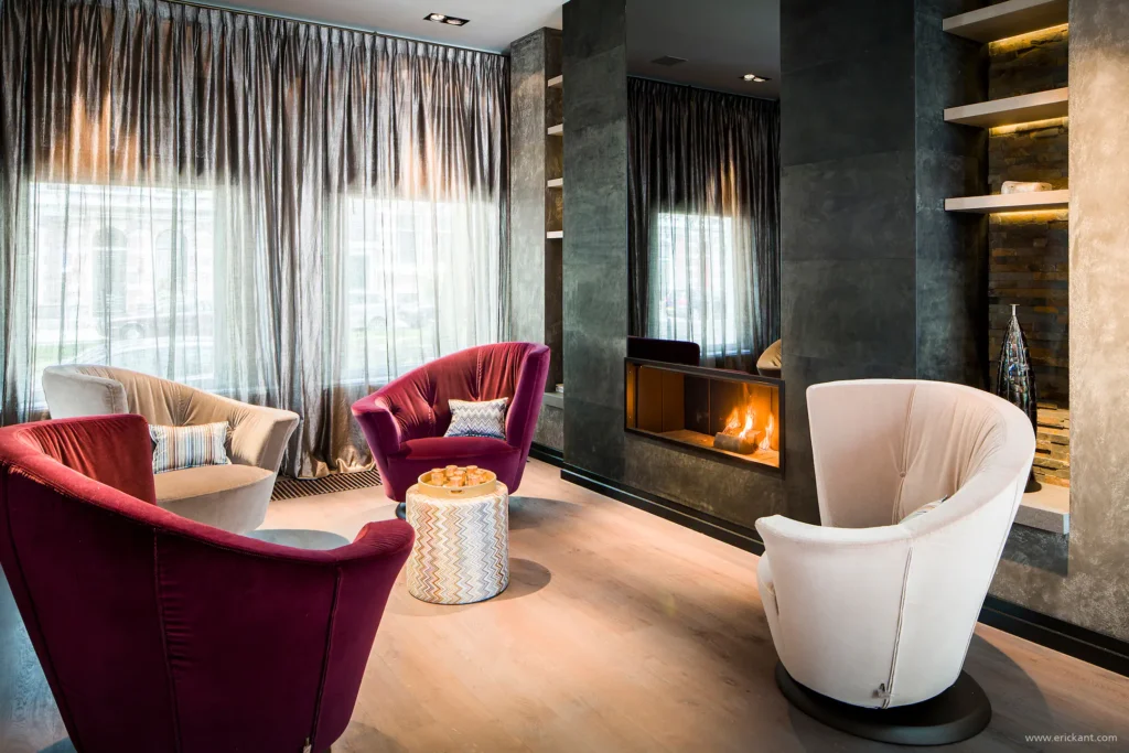 High-end lounge in Riga met moderne gashaard, luxe velvet fauteuils in bordeaux en crème, en glanzende gordijnen door ERIC KANT.