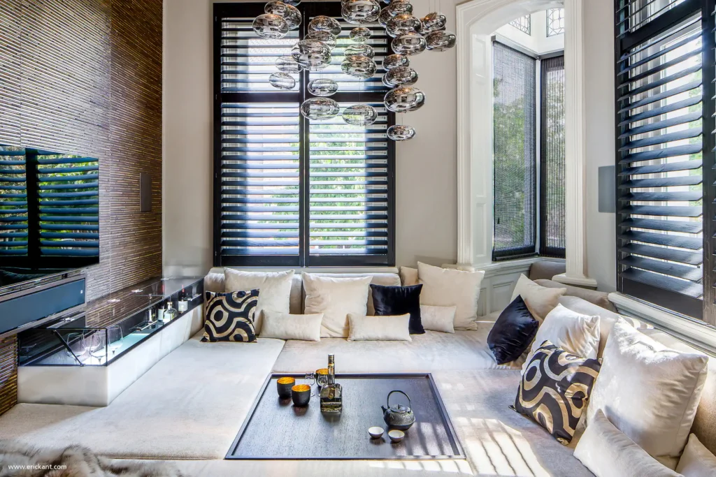 High-end verzonken loungehoek in Riga met maatwerk bank, glazen hanglampen, zwarte houten shutters en een verborgen bar door ERIC KANT.