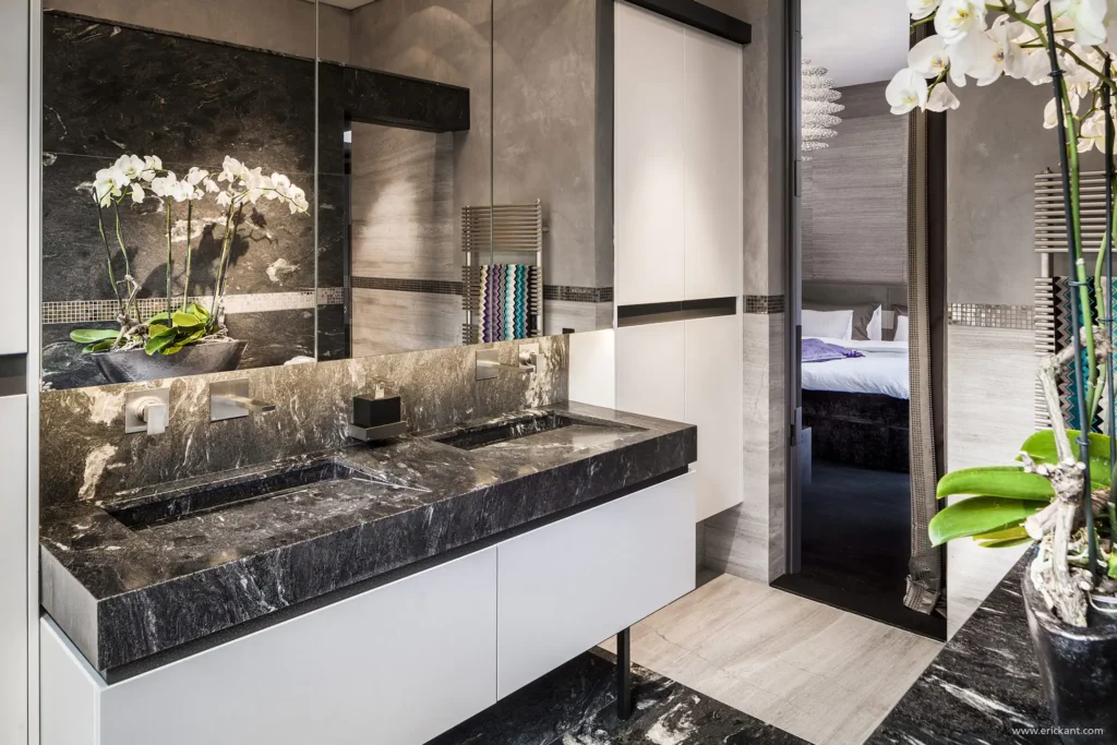 High-end badkamer in Riga met dubbele marmeren wastafel, grote spiegelwand en doorkijk naar de master bedroom door ERIC KANT.