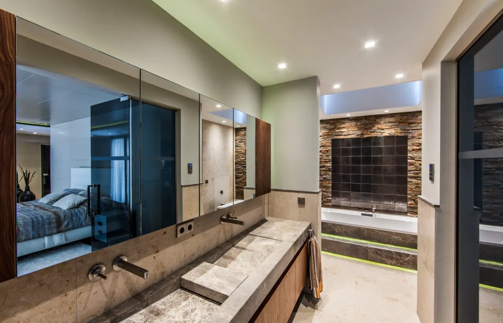 High-end badkamer in het Luxury Bungalow project door ERIC KANT met een natuurstenen wastafel, een wand van ruwe natuursteen bij het ligbad, een dakraam en indirecte verlichting.