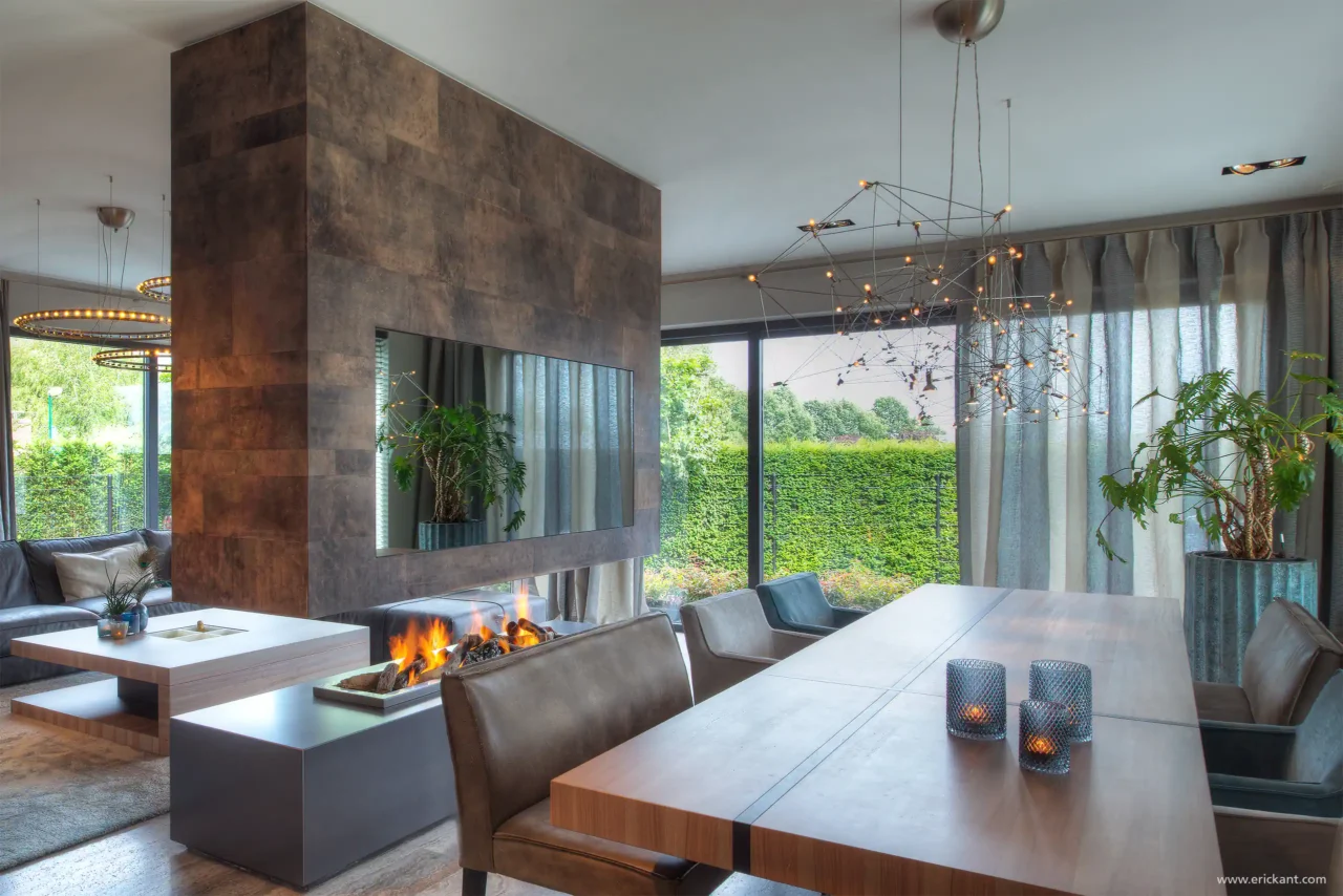 High-end interieur van de Mediterranean Holland villa door ERIC KANT met een doorkijkhaard in bronzen lederlook, een robuuste houten eettafel, designverlichting en grote glaspartijen naar de tuin.