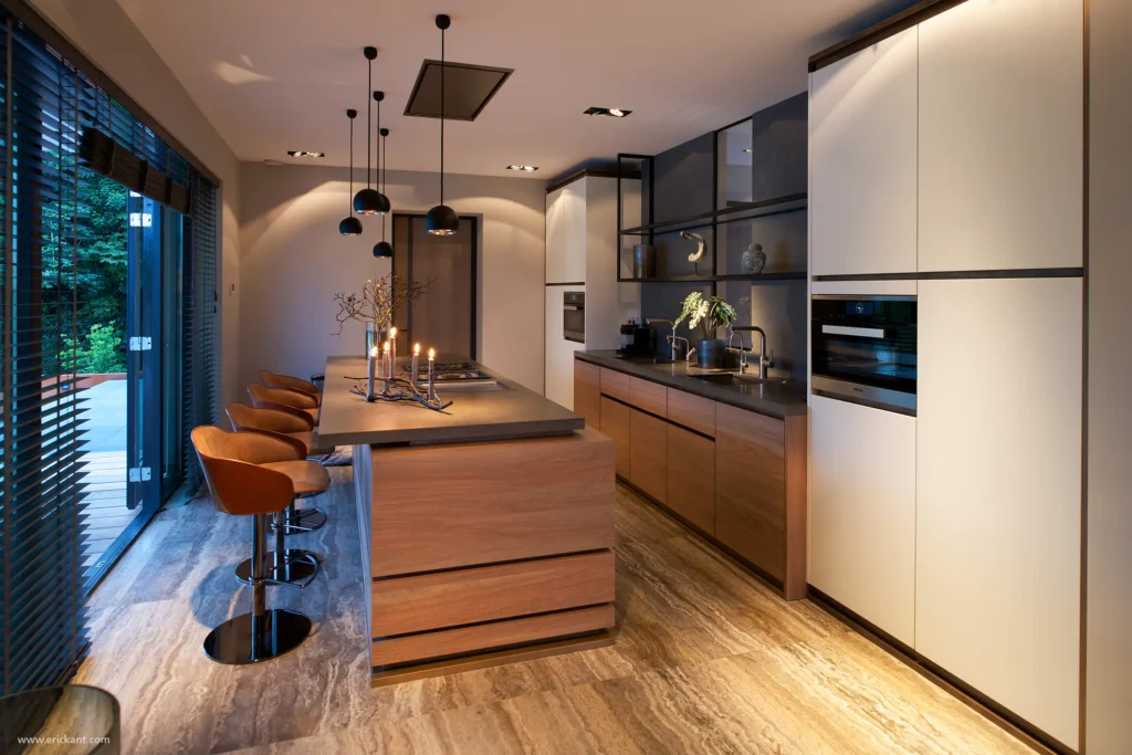 High-end keuken van de Mediterranean Holland villa door ERIC KANT met een kookeiland in eikenhout, natuurstenen vloer, witte kastenwanden en sfeervolle verlichting met zwarte hanglampen en kaarsen