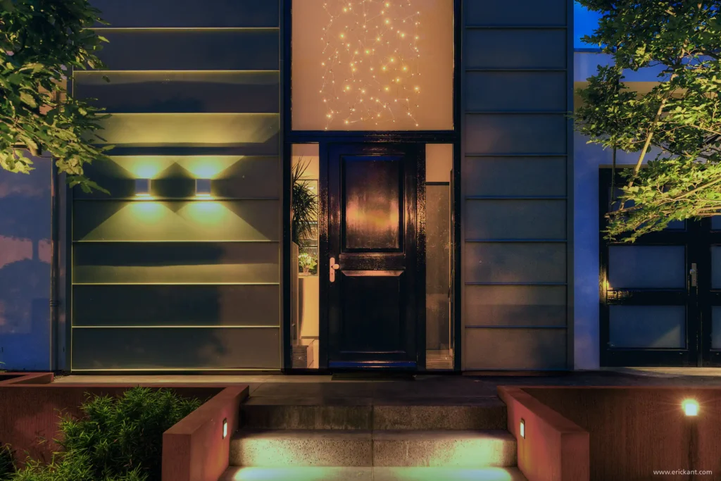 High-end entree van de Mediterranean Holland villa door ERIC KANT bij avond, met een hoogglans zwarte voordeur, monumentaal raam met sterrenverlichting, cortenstaal borders en strakke gevelverlichting.