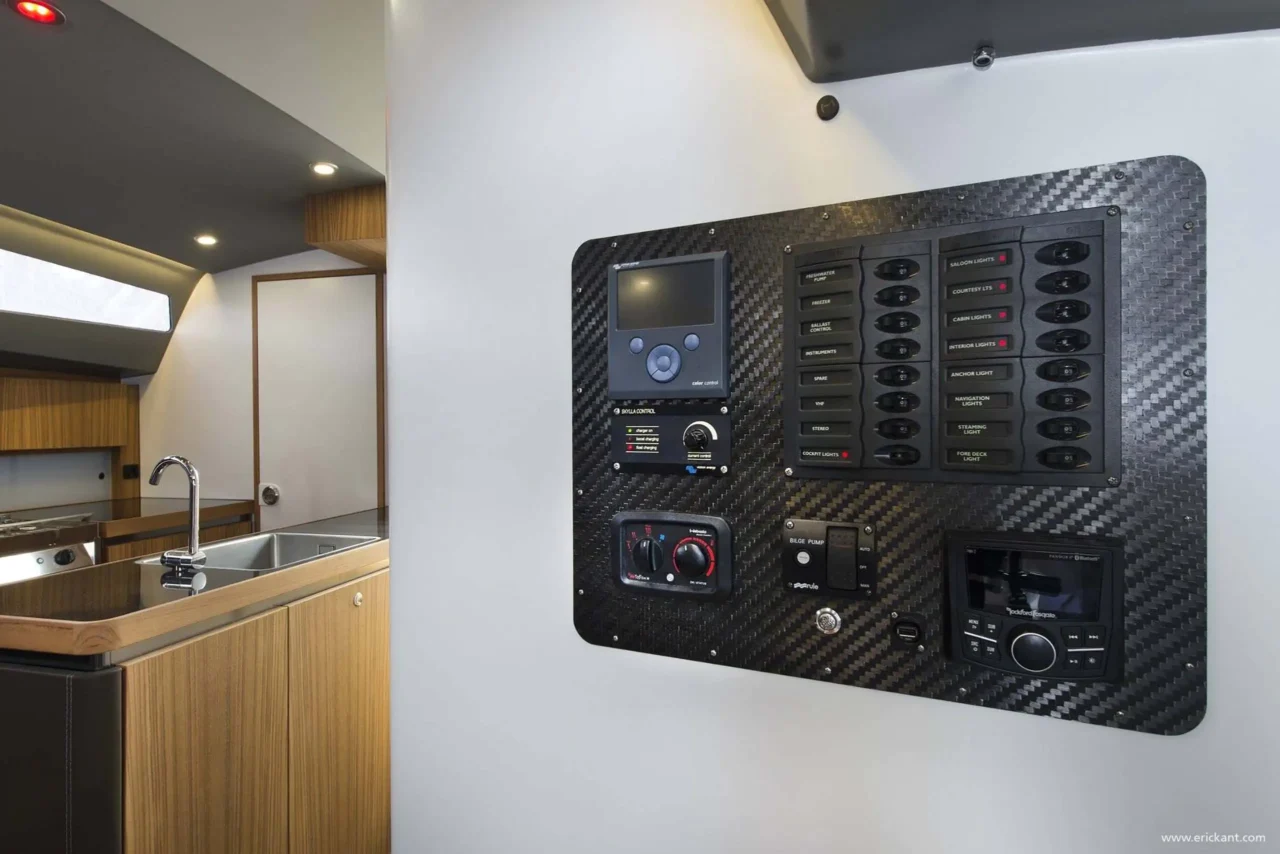 Hoogwaardig detail van een jachtinterieur ontworpen door Eric Kant, com uma tela de navegação digital e controles em um console de couro marrom costurado à mão, com acabamentos em madeira de nogueira.