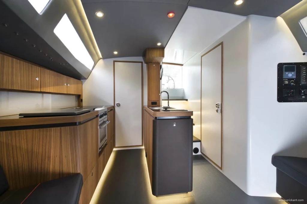 Modern interieur van een Agile Yacht ontworpen door Eric Kant, met een compacte houten keuken, rvs spoelbak, geïntegreerde oven en sfeervolle led-verlichting onder de kasten.