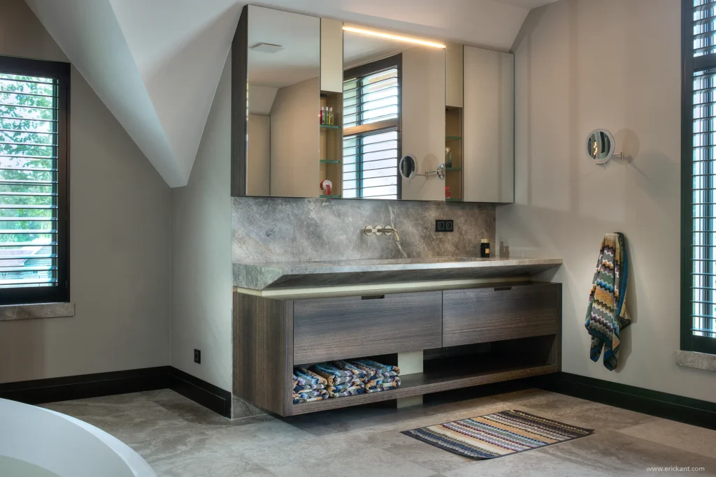 High-end badkamerinterieur van de Modern Manor met een dubbele wastafel van natuursteen, eikenhouten onderkast, kamerhoge spiegels met verticale LED-strips en bronzen kranen door ERIC KANT.