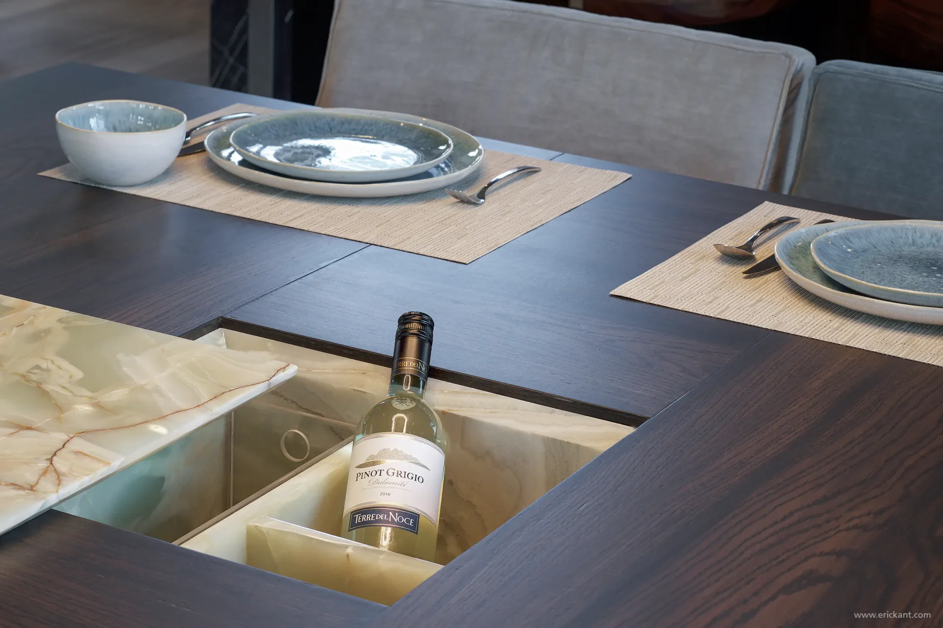 Detail van een maatwerk eettafel in de Mansion on the Waterfront door ERIC KANT met een ingebouwde wijnkoeler van verlicht natuursteen, donker eikenhout en verfijnd servies.