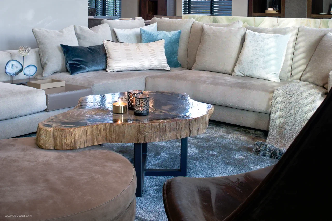 Detail van de zithoek in de Mansion on the Waterfront door ERIC KANT met een grote grijze loungebank, blauwe fluwelen kussens en een unieke salontafel van versteend hout.