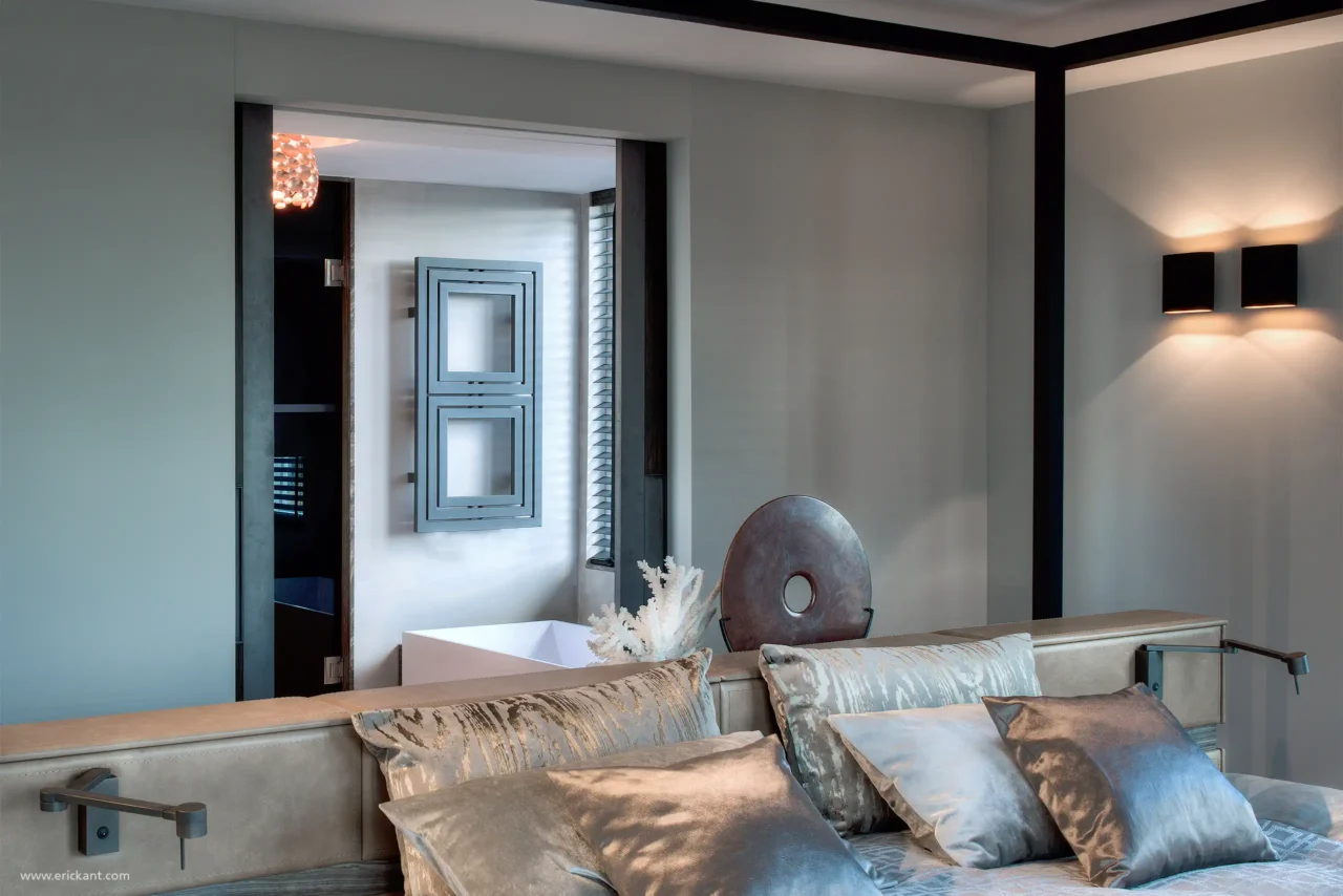 Detailbeeld van de master bedroom in de Mansion on the Waterfront door ERIC KANT, met zicht op de luxe badkamer, een lederen hoofdbord met leeslampjes en moderne wandverlichting.