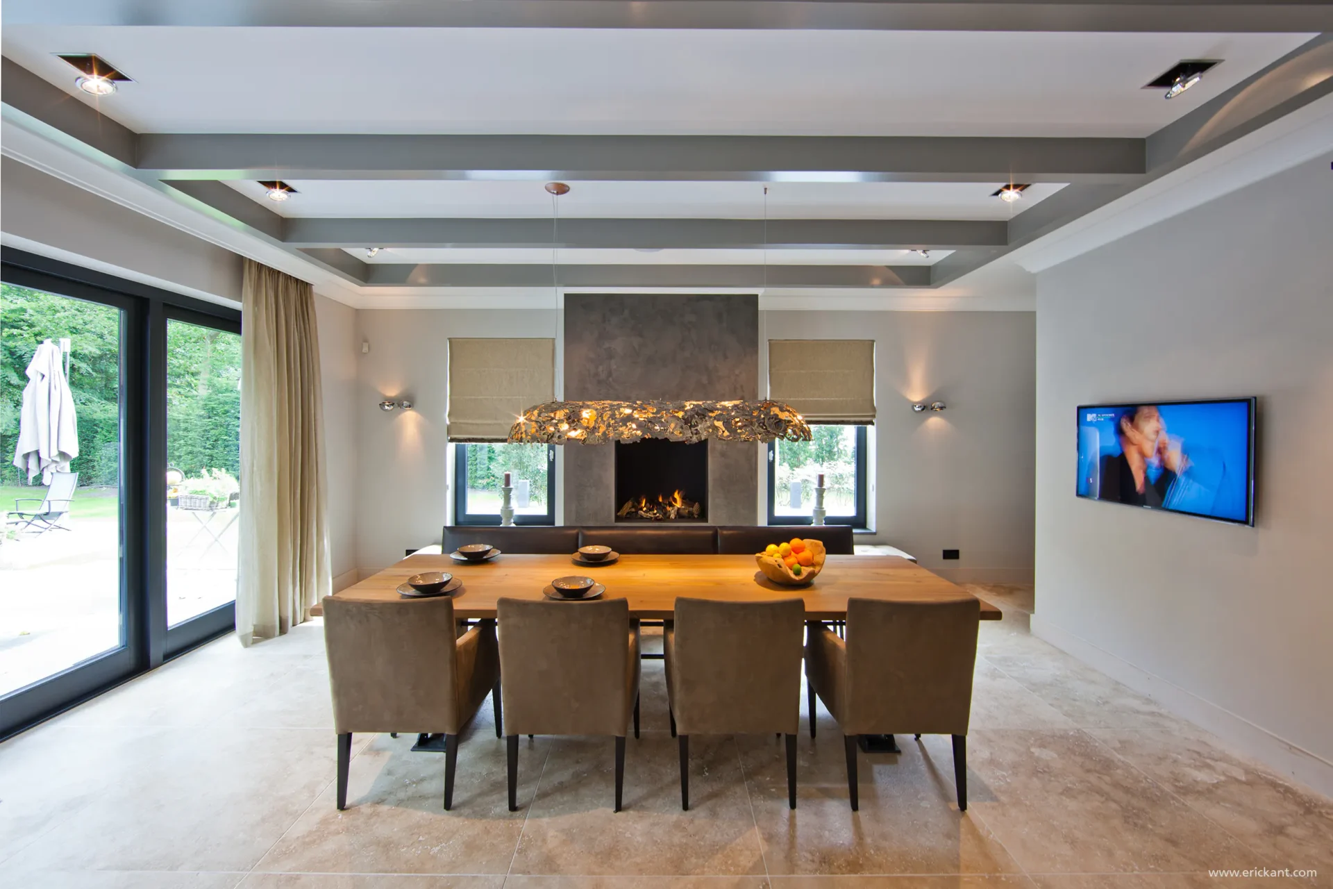 High-end eetkamerinterieur van project New Classic Villa met een houten tafel, donkere marmeren haardpartij en een glimp van de keuken door ERIC KANT.