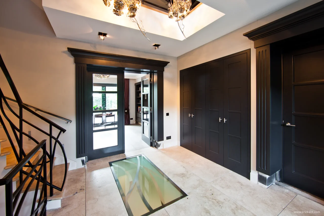 High-end eetkamerinterieur van project New Classic Villa met een houten tafel, moderne haardpartij, sculpturale verlichting en zicht op de tuin door ERIC KANT.