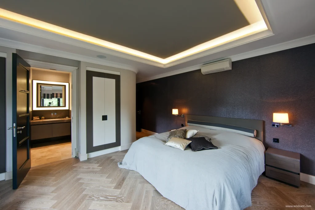 High-end slaapkamerinterieur in project New Classic Villa met een visgraatvloer, verlicht koofplafond, getextureerd behang en doorkijk naar de badkamer door ERIC KANT.