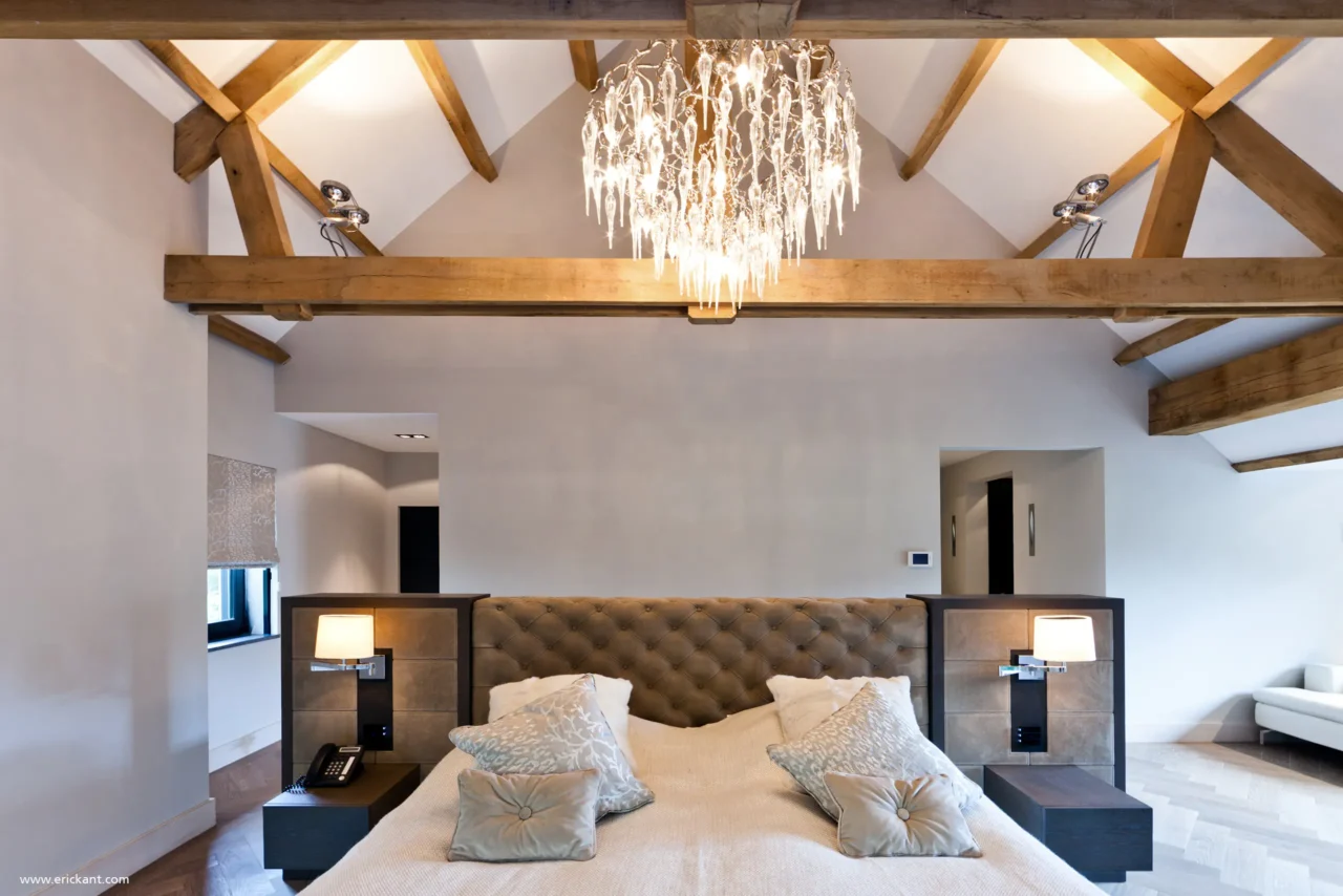 High-end master bedroom van project New Classic Villa met eikenhouten spanten, een kristallen kroonluchter, gecapitonneerd hoofdbord en visgraatvloer door ERIC KANT.