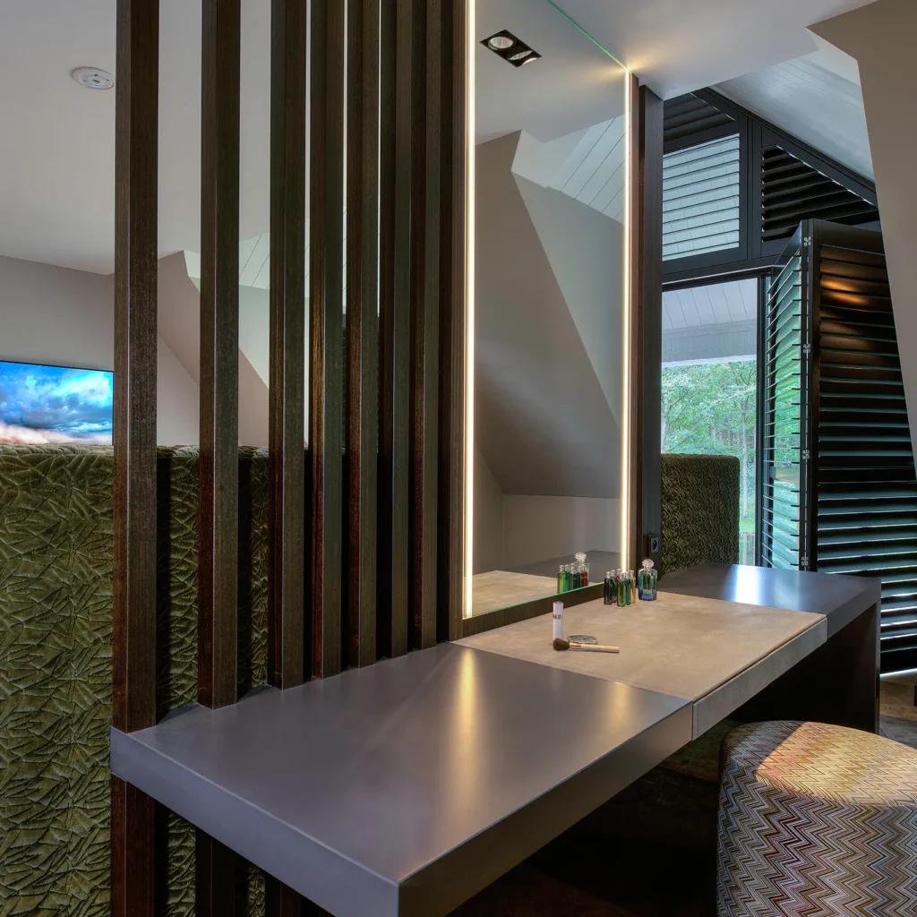 High-end make-up tafel in de Modern Manor met een verlichte spiegel, donkere houten lamellen als roomdivider, lederen werkblad en een Missoni-stijl poef door ERIC KANT.