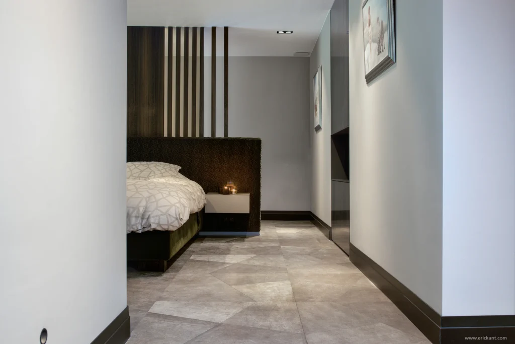 High-end master bedroom van de Modern Manor met een unieke geometrische natuurstenen vloer, een gestoffeerd hoofdbord, houten lamellen roomdivider en zwevende nachtkastjes door ERIC KANT.