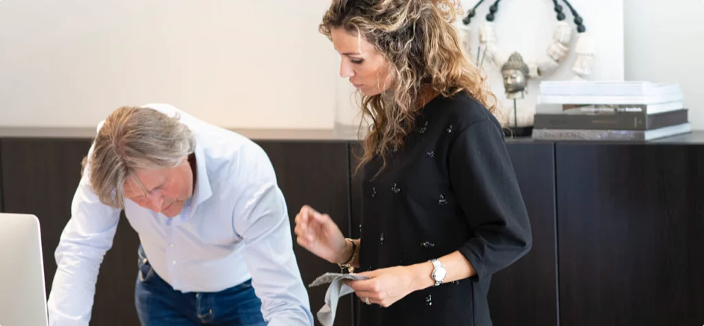 Eric Kant en Naomi Donkersloot aan het werk in de ontwerpstudio, stalen van materialen bekijkend voor een luxe interieurproject.