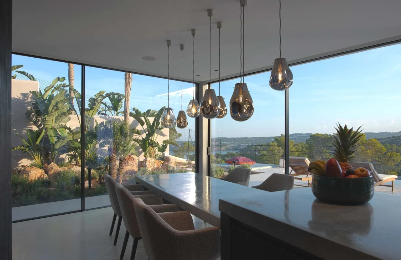 High-end eetkamer met glazen wanden, Bocci hanglampen en uitzicht op de natuur in project Cali Moli Ibiza door ERIC KANT.