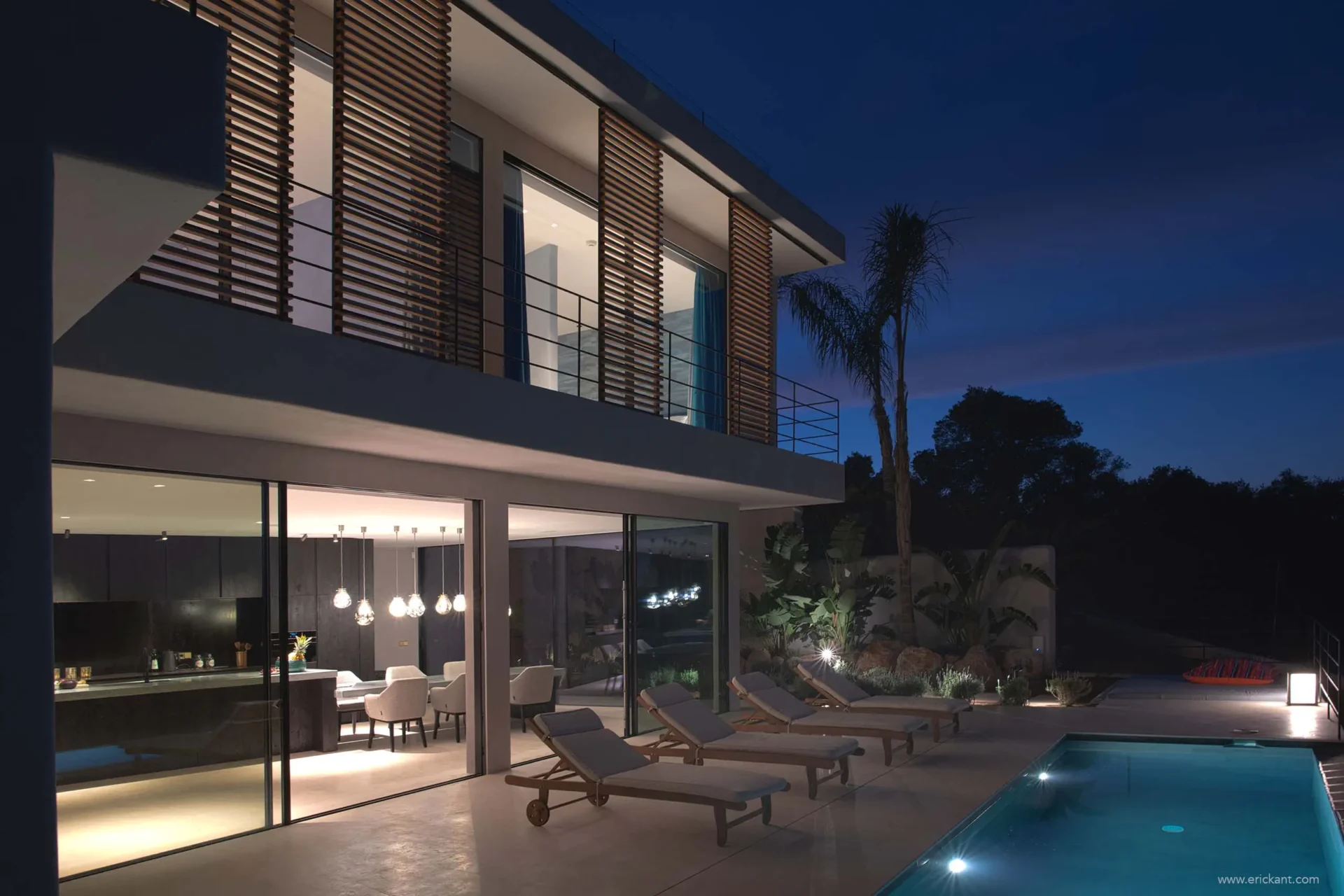Luxe moderne villa in Ibiza bij nacht met verlicht zwembad, design buitenmeubilair en glazen gevel door ERIC KANT.