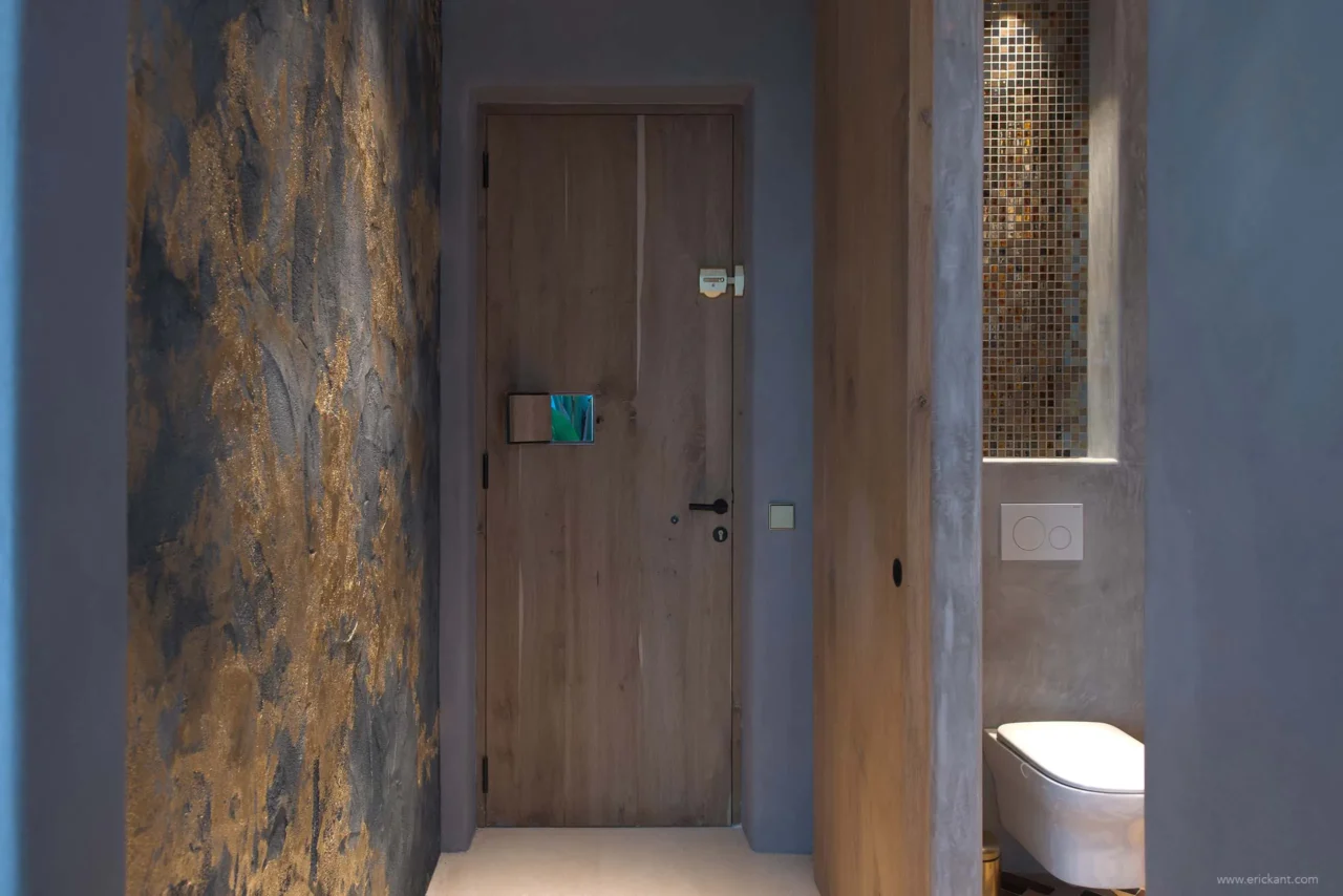 Luxe interieur met Dofine wandafwerking, maatwerk houten deur en design toilet in project Cali Moli Ibiza door ERIC KANT.