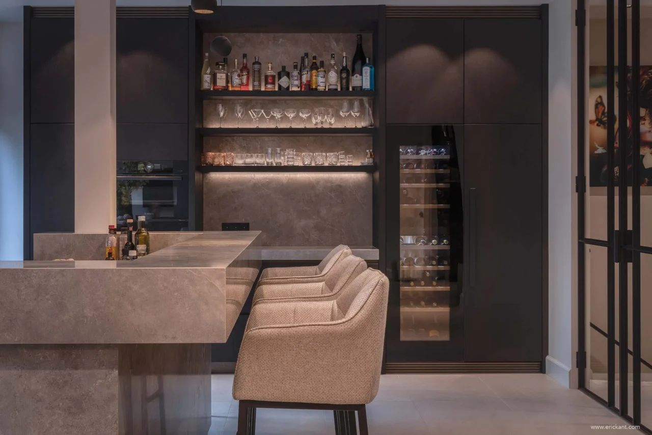 High-end keukeninterieur van de Modern Townhouse Amsterdam met een marmeren bar, fluwelen barkrukken, een verlichte achterwand met sterke drank en een geïntegreerde wijnklimaatkast door ERIC KANT