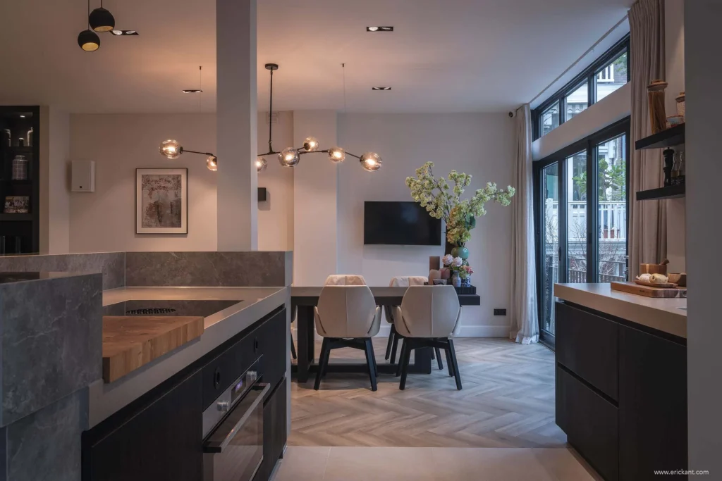 High-end keukeninterieur van de Modern Townhouse Amsterdam met een marmeren werkblad, houten snijblok, visgraatvloer en zicht op de eethoek met designverlichting door ERIC KANT.