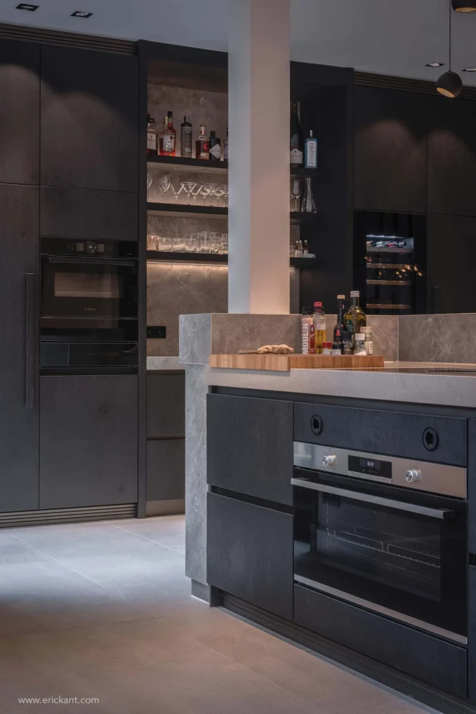 Modern keukeninterieur van project Modern Townhouse Amsterdam met zwarte houten kasten, een marmeren kookeiland, ingebouwde ovens en een verlichte bar-nis door ERIC KANT.
