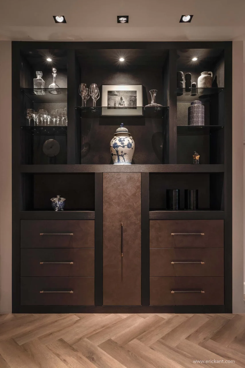 High-end maatwerk kast in project Modern Townhouse Amsterdam met donker hout, lederen fronten, geïntegreerde verlichting en decoratieve objecten door ERIC KANT.
