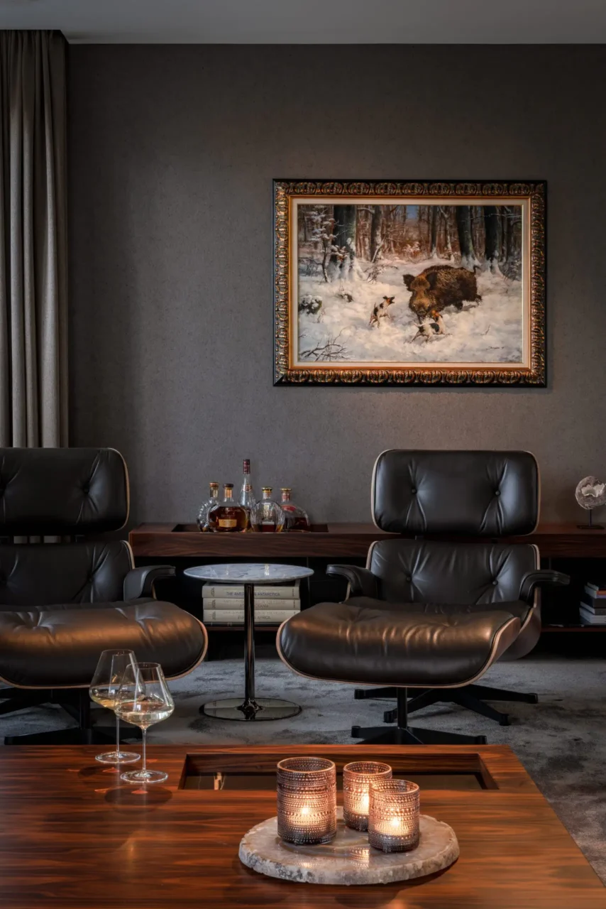 High-end loungehoek in de Modern Classic Villa met twee Vitra Eames Lounge Chairs, een klassiek jachtschilderij, een donker houten dressoir met exclusieve dranken en sfeervolle kaarsen door ERIC KANT.
