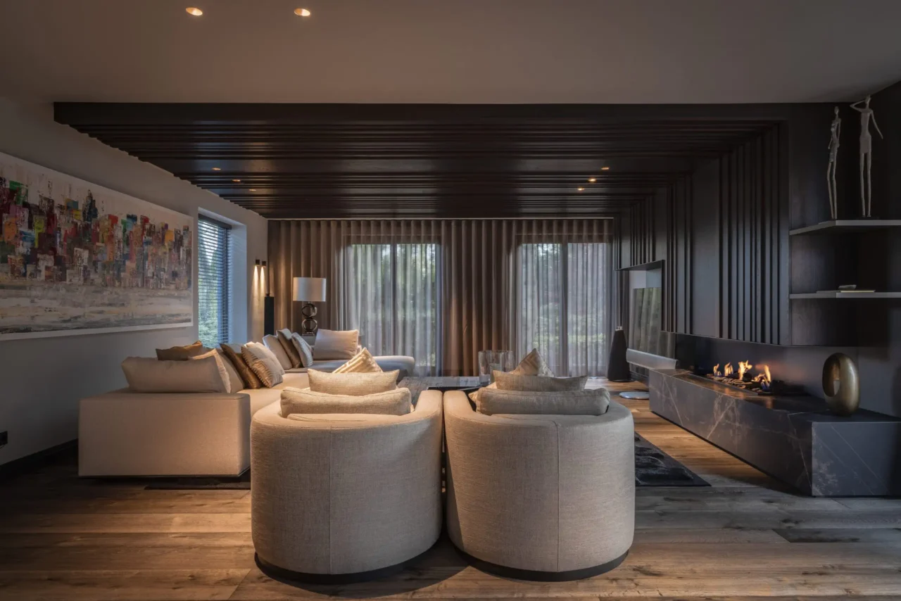 High-end en-suite badkamer in de Metropolitan Luxury villa met een opvallend rond, donker eikenhouten wastafelmeubel, een grote organisch gevormde spiegel met LED-verlichting, een vrijstaand bad en travertijn-look wanden door ERIC KANT.