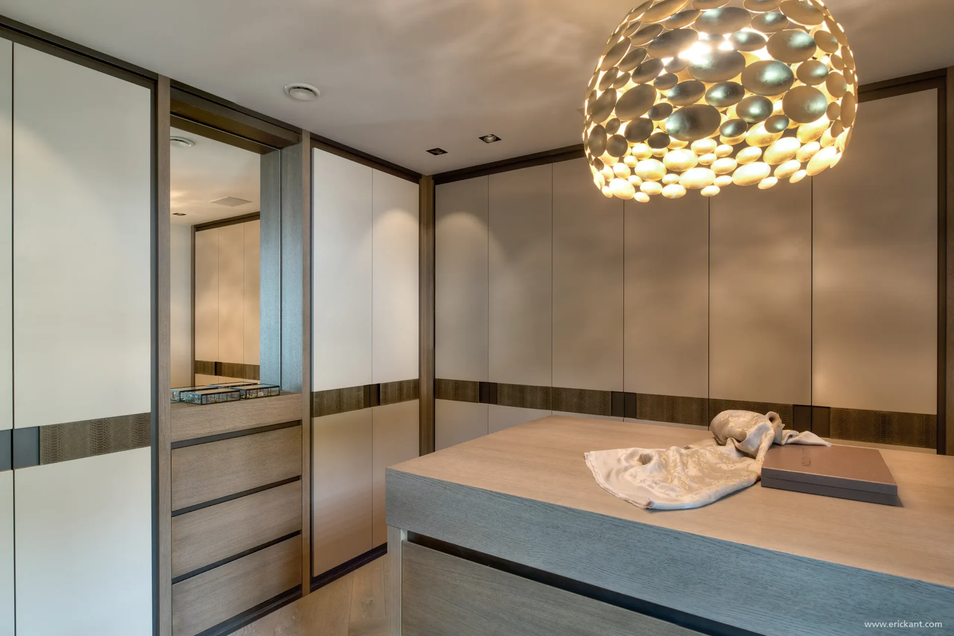 High-end inloopkast in de Manor Villa door ERIC KANT met kamerhoge maatwerk kasten, lederen details, een centraal lade-eiland en een goudkleurige designlamp.