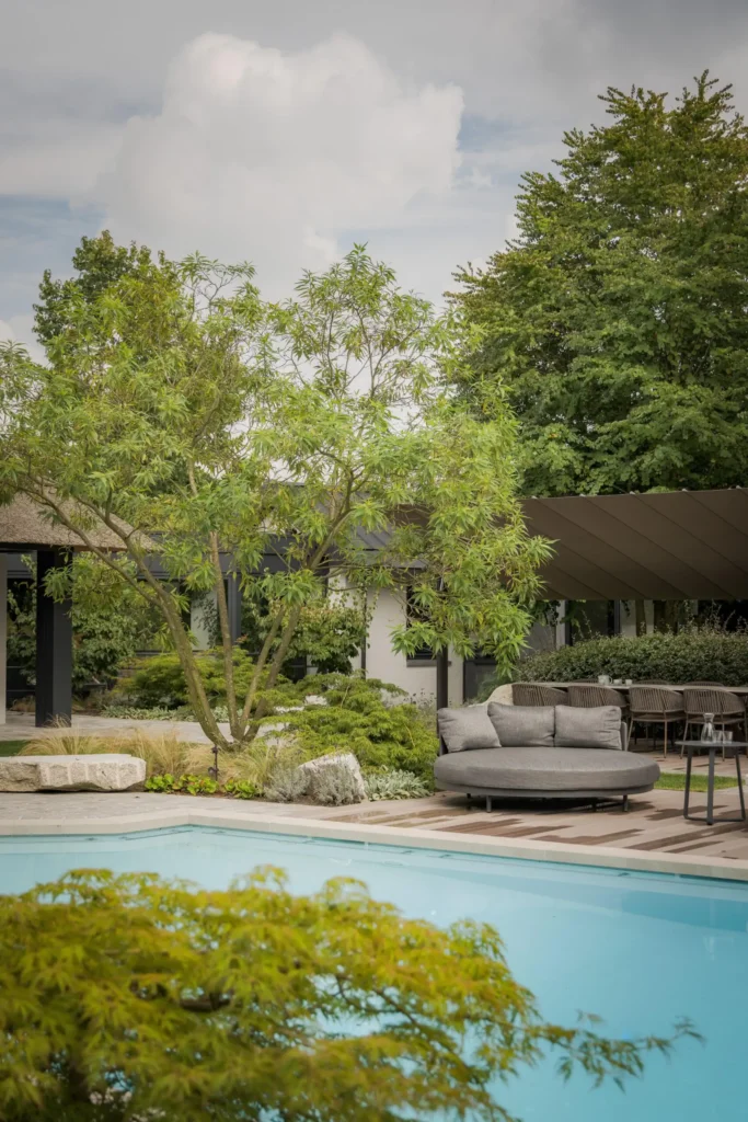 Exclusieve lodge-architectuur door Eric Kant, met een robuuste eikenhouten overkapping, luxe buitenmeubelen en een strak gazon op de voorgrond.