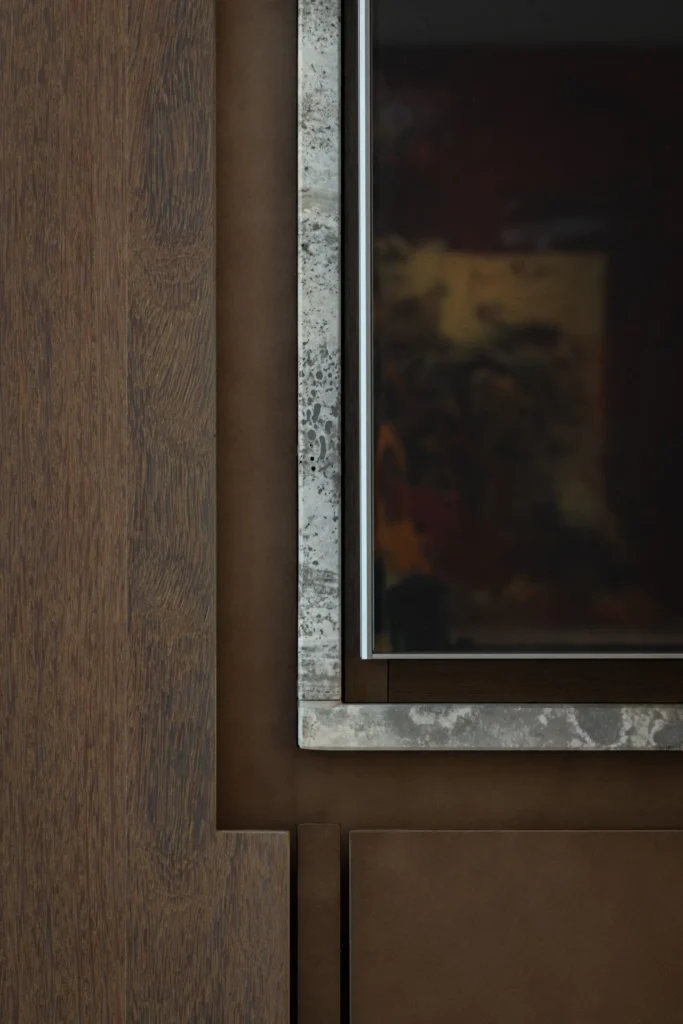 Detailopname in Villa Essenza door ERIC KANT van het samenspel tussen donker eikenhout, zacht leer en geaderd marmer in een maatwerk interieurelement.